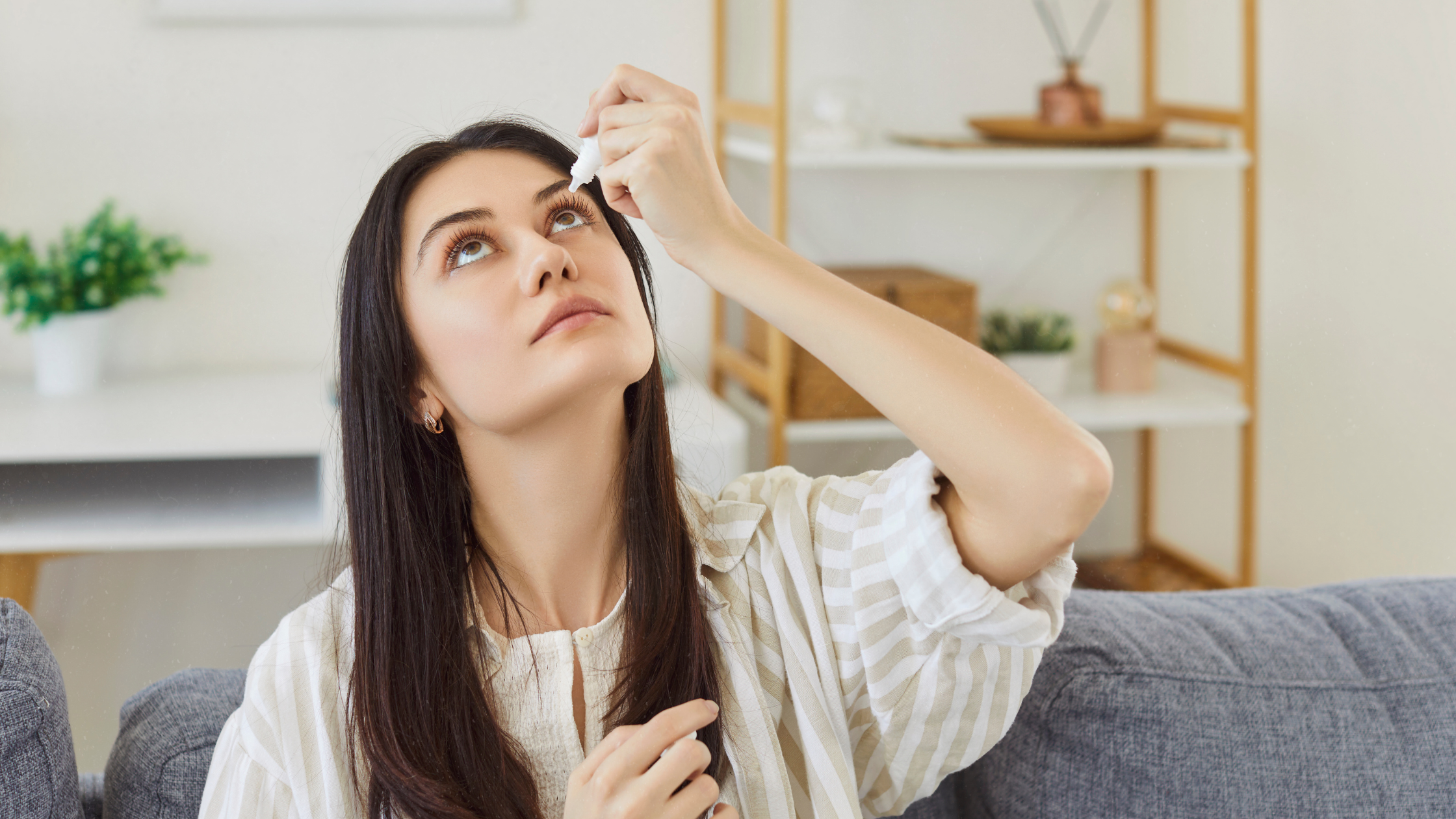 Application of eye drops with hyaluronic acid for dry eyes by a woman